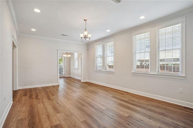 unfurnished room featuring an inviting chandelier, hardwood / wood-style floors, a healthy amount of sunlight, and crown molding