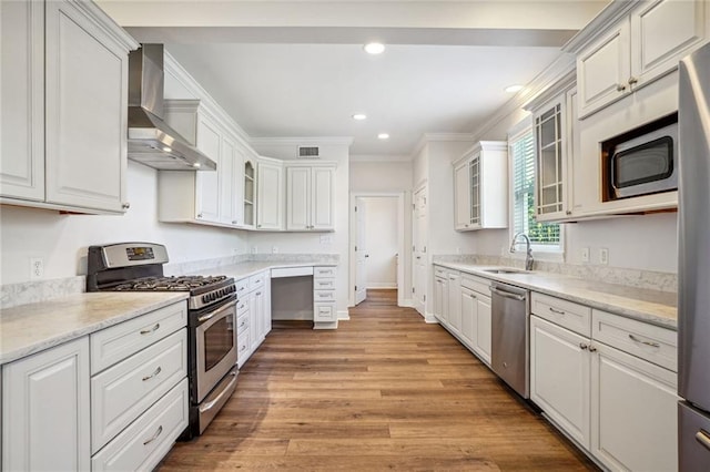 kitchen featuring appliances with stainless steel finishes, white cabinetry, and wall chimney range hood