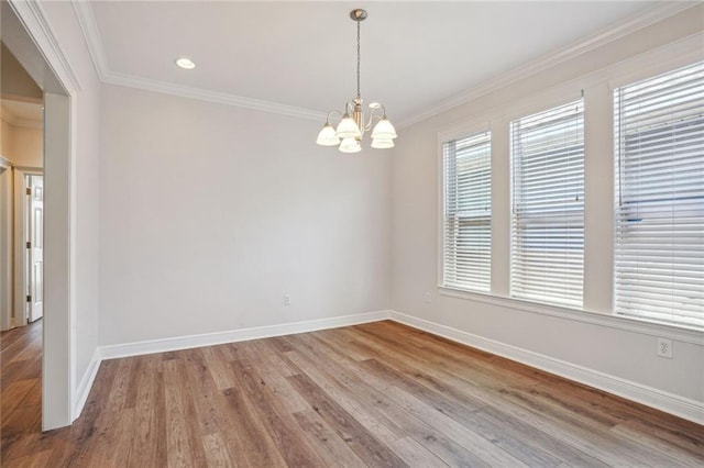 empty room featuring ornamental molding, wood-type flooring, and an inviting chandelier