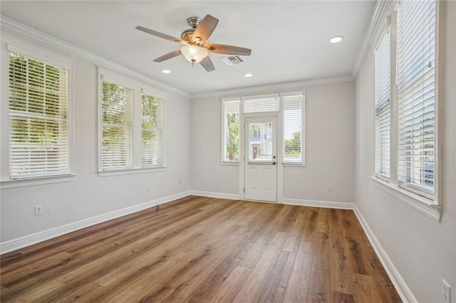 empty room with crown molding, a healthy amount of sunlight, hardwood / wood-style flooring, and ceiling fan