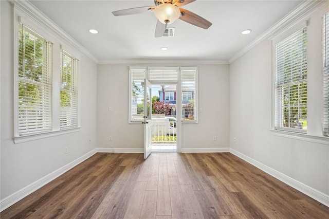 spare room with dark wood-type flooring, a healthy amount of sunlight, and ornamental molding