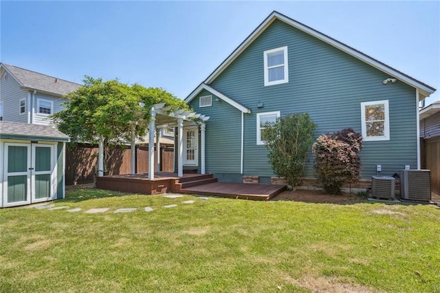 back of property with a wooden deck, central AC unit, a pergola, a storage unit, and a lawn