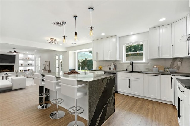 kitchen with a healthy amount of sunlight, white cabinetry, hanging light fixtures, and a fireplace