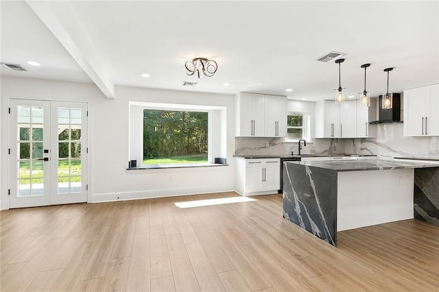 kitchen with white cabinets, dark stone countertops, light hardwood / wood-style floors, and wall chimney range hood