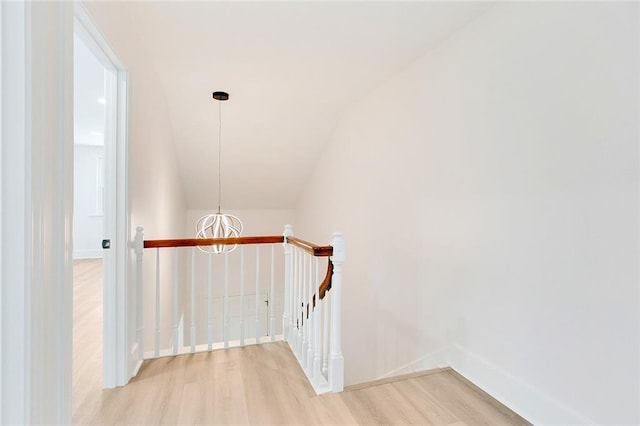 hall with an inviting chandelier, vaulted ceiling, and hardwood / wood-style floors