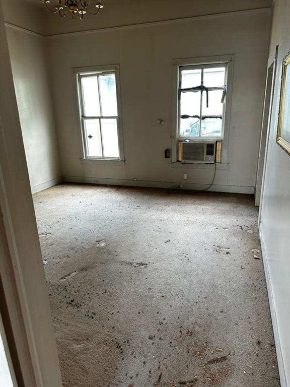 empty room featuring an inviting chandelier, a wealth of natural light, and light colored carpet