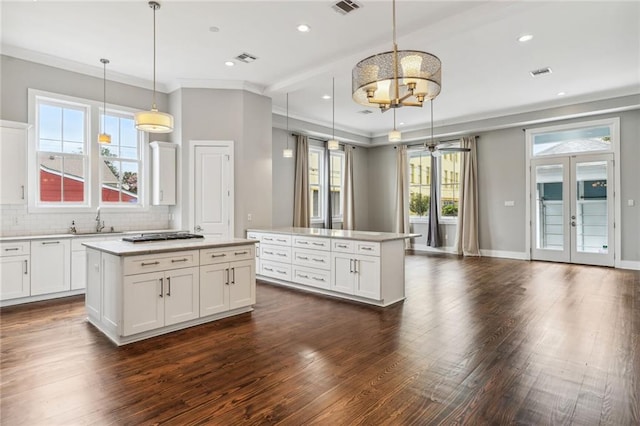 kitchen with hanging light fixtures, a kitchen island, dark hardwood / wood-style flooring, and white cabinets