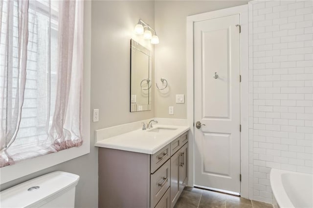 bathroom with a bathtub, vanity, toilet, and tile patterned floors