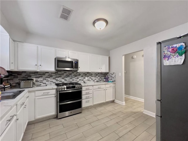 kitchen featuring white cabinets, stainless steel appliances, and tasteful backsplash