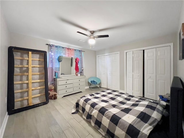 bedroom featuring ceiling fan, two closets, and light hardwood / wood-style flooring