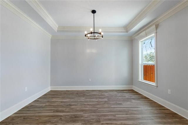 unfurnished room featuring an inviting chandelier, a raised ceiling, ornamental molding, and dark hardwood / wood-style flooring