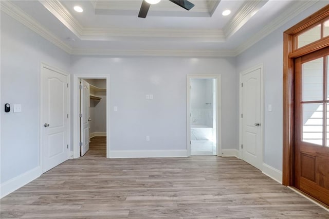 interior space with crown molding, light hardwood / wood-style floors, a tray ceiling, and ceiling fan