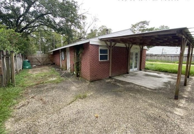 103 W Hickory St, Mandeville, LA 70471 - view of property exterior featuring a patio area, a carport, brick siding, french doors, and fence