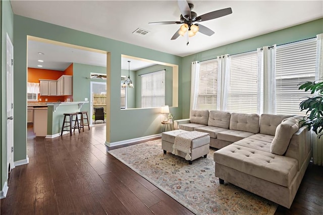 living room with ceiling fan with notable chandelier and dark wood-type flooring