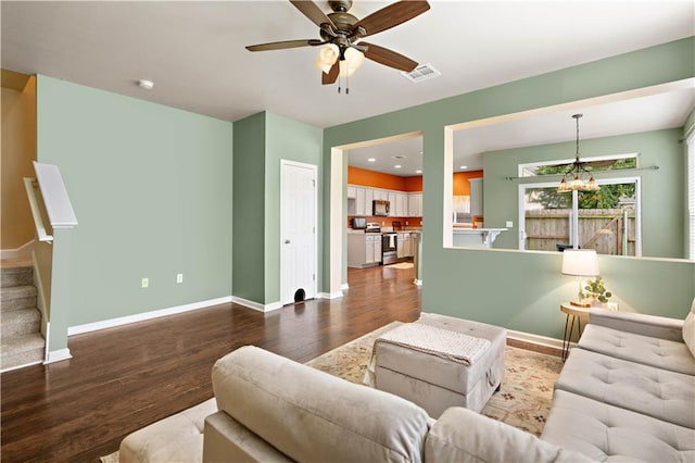 living room with ceiling fan with notable chandelier and hardwood / wood-style flooring