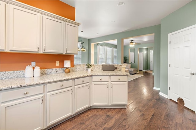 kitchen featuring ceiling fan, pendant lighting, light stone counters, white cabinetry, and dark hardwood / wood-style floors