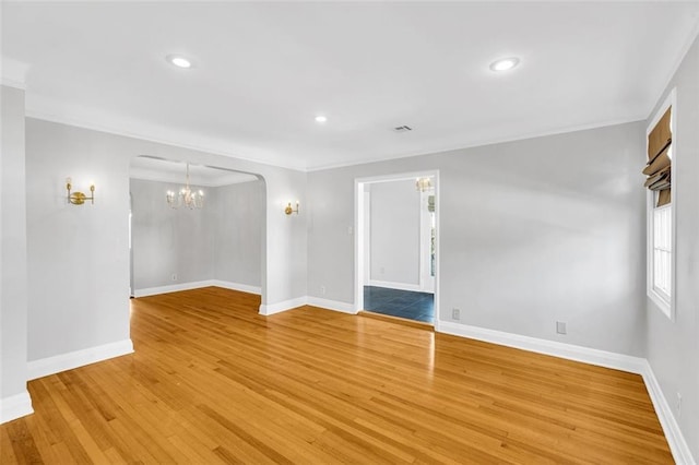 empty room featuring ornamental molding, a notable chandelier, and hardwood / wood-style flooring