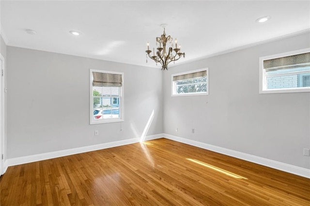 spare room featuring wood-type flooring and a chandelier