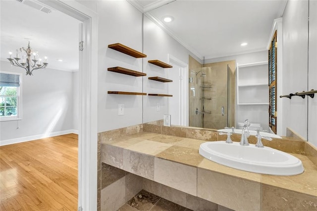 bathroom featuring sink, ornamental molding, hardwood / wood-style flooring, walk in shower, and a notable chandelier