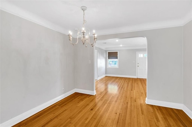 spare room featuring crown molding, light hardwood / wood-style floors, and a chandelier