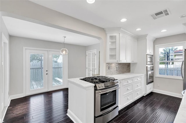 kitchen featuring appliances with stainless steel finishes, white cabinetry, backsplash, pendant lighting, and dark hardwood / wood-style floors