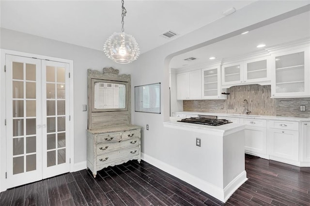 kitchen with tasteful backsplash, stainless steel gas stovetop, white cabinetry, decorative light fixtures, and dark hardwood / wood-style flooring