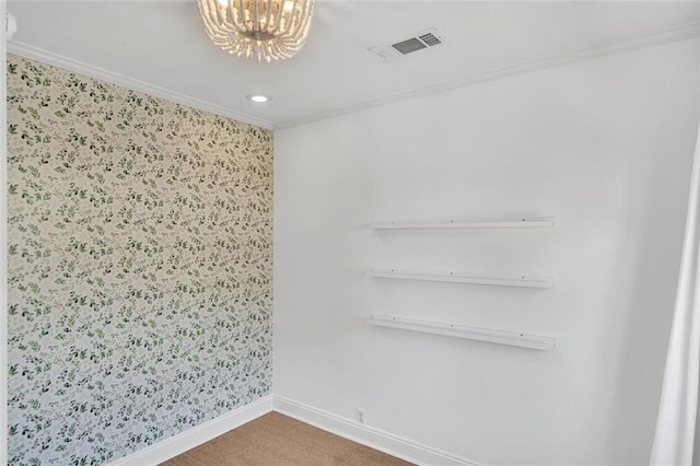 spare room featuring ornamental molding, a chandelier, and carpet