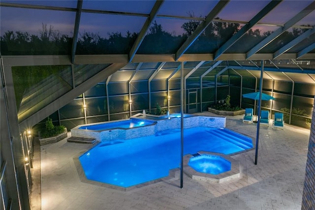 pool at dusk with a lanai, a patio, and an in ground hot tub