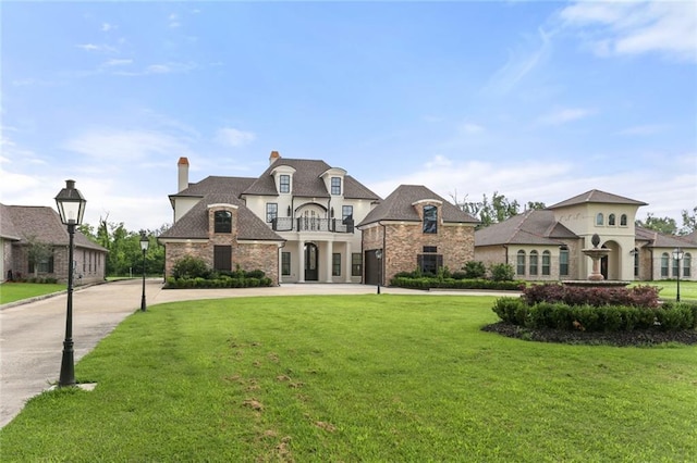 french country home featuring a balcony and a front lawn