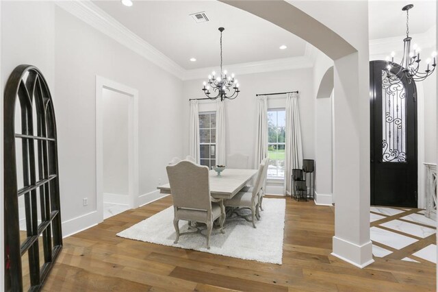 dining area featuring an inviting chandelier, hardwood / wood-style flooring, and crown molding