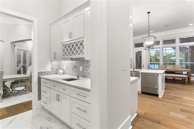 kitchen with sink, decorative light fixtures, light hardwood / wood-style floors, and white cabinetry