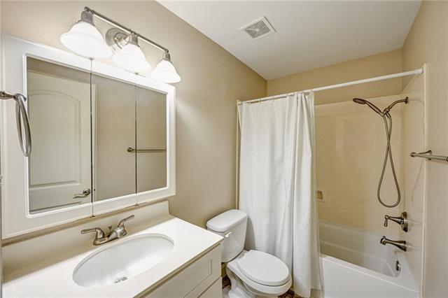 full bathroom with shower / bathtub combination with curtain, toilet, and vanity