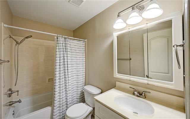 full bathroom with shower / bath combination with curtain, vanity, and toilet