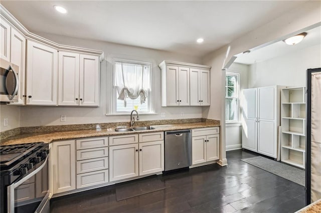 kitchen with dark wood-type flooring, white cabinets, stainless steel appliances, and sink