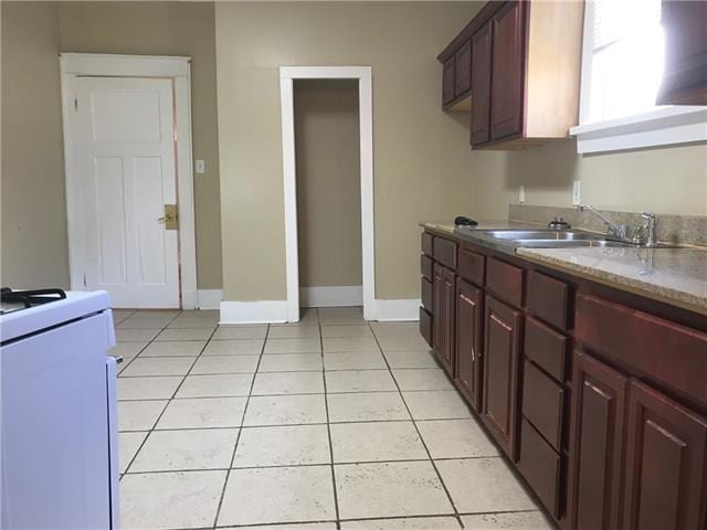 kitchen featuring light tile patterned flooring, stove, and sink