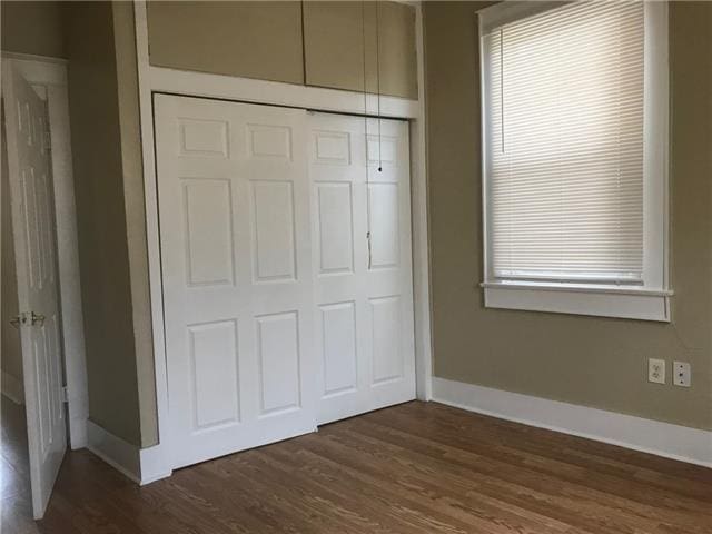 unfurnished bedroom with dark hardwood / wood-style floors and a closet