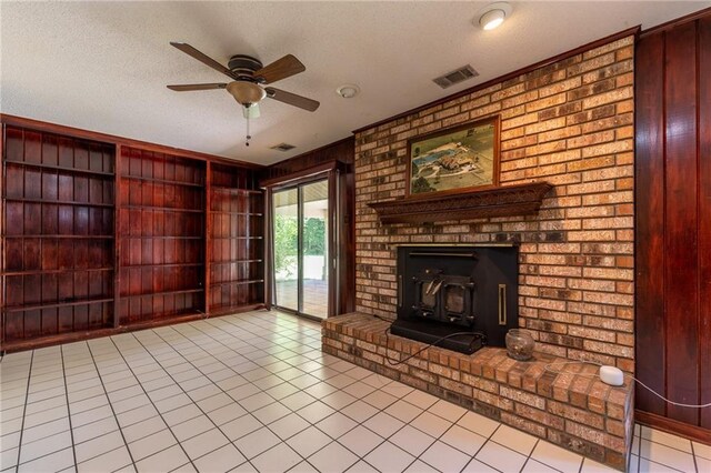 unfurnished living room featuring ceiling fan, a textured ceiling, a fireplace, and light tile patterned flooring