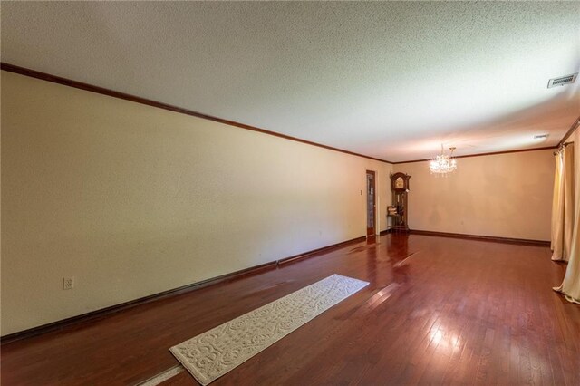 interior space with an inviting chandelier, a textured ceiling, hardwood / wood-style floors, and crown molding