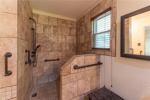 bathroom with a textured ceiling and a tile shower