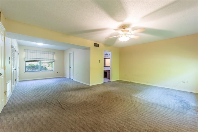 empty room with dark colored carpet, ceiling fan, and a textured ceiling