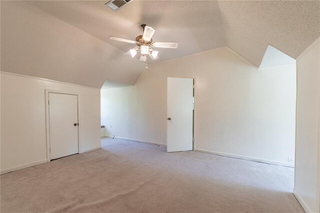 bonus room featuring a textured ceiling, lofted ceiling, ceiling fan, and light colored carpet