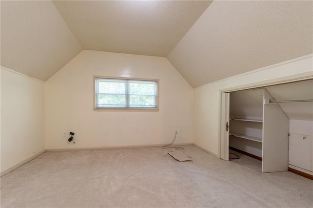 bonus room with a textured ceiling, lofted ceiling, and light colored carpet