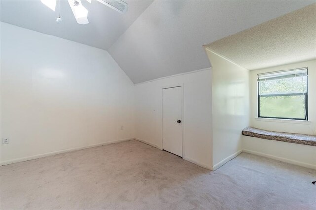 additional living space featuring lofted ceiling, ceiling fan, light colored carpet, and a textured ceiling