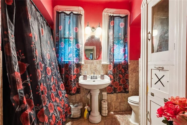 bathroom with tile walls, toilet, and curtained shower