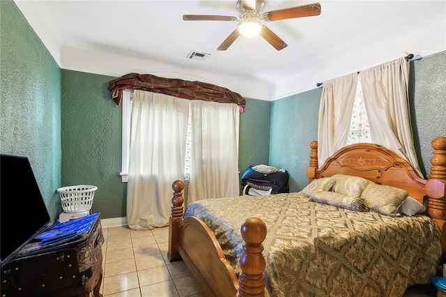 bedroom featuring a ceiling fan, tile patterned floors, a textured wall, and visible vents