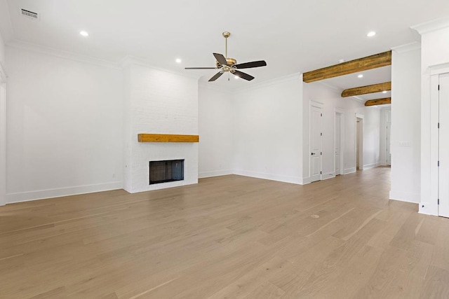 unfurnished living room with ceiling fan, beam ceiling, a large fireplace, light wood-type flooring, and crown molding