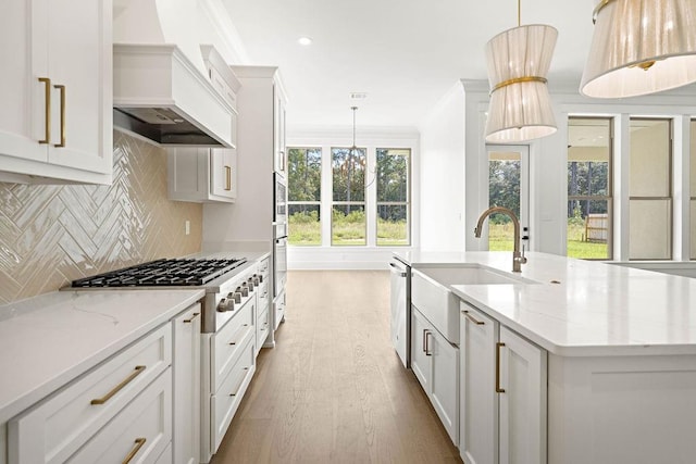 kitchen with decorative light fixtures, premium range hood, light stone countertops, and a wealth of natural light