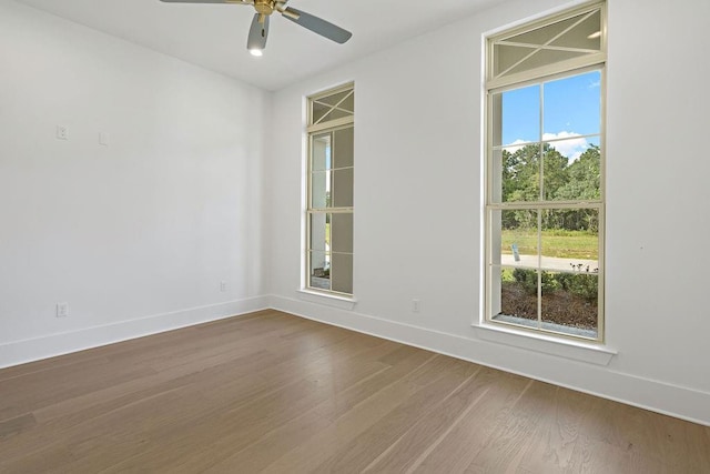 spare room with ceiling fan, hardwood / wood-style flooring, and a wealth of natural light