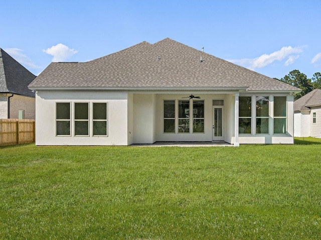 rear view of property featuring a lawn and ceiling fan