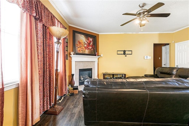 living room featuring ceiling fan, ornamental molding, a tiled fireplace, and dark hardwood / wood-style flooring